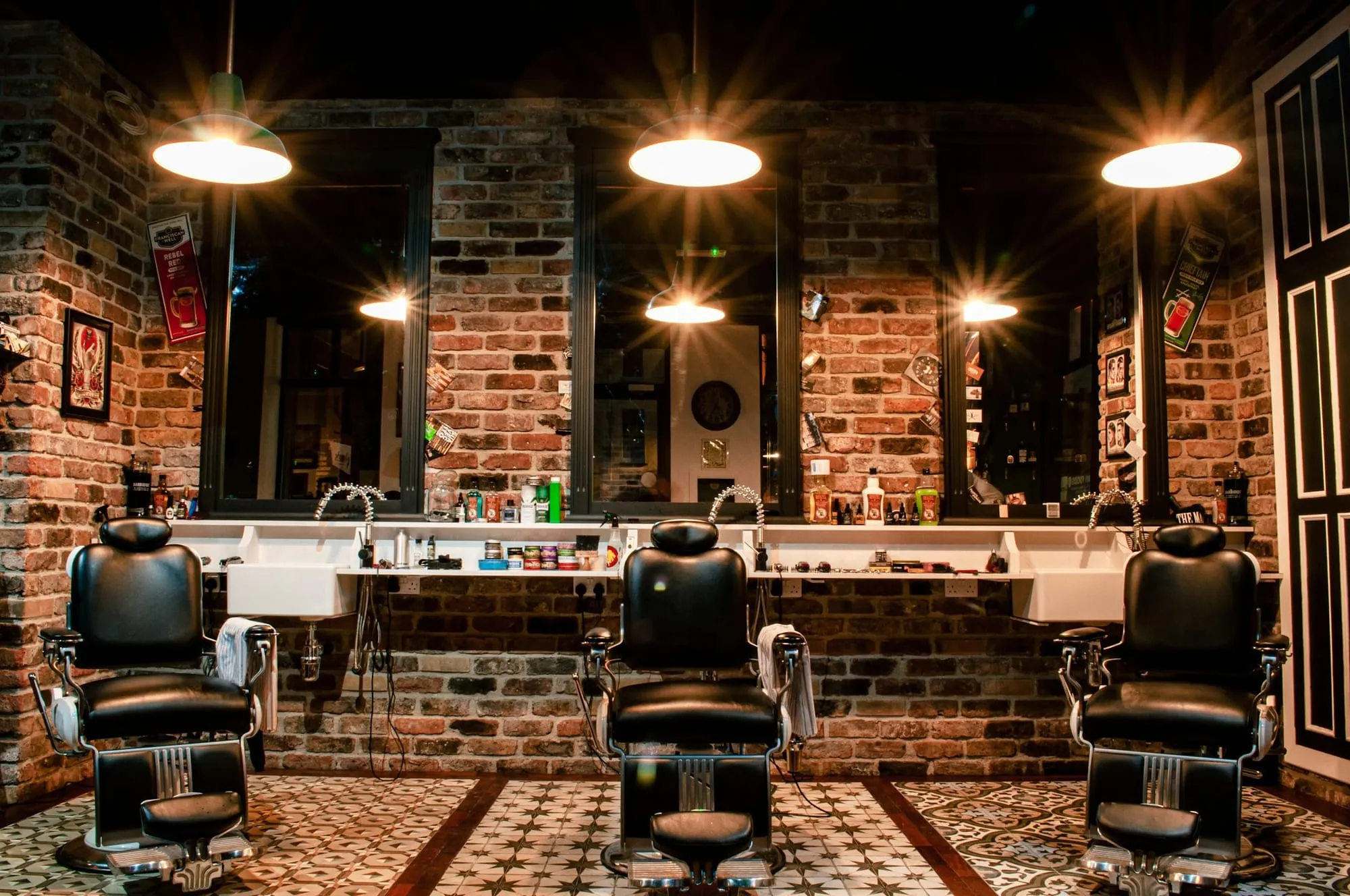Three vintage barber chairs in front of a brick wall